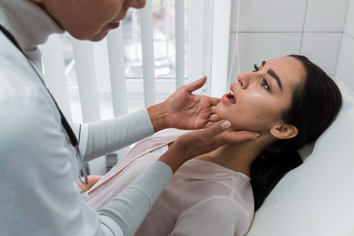 Doctor examining patient’s jaw and mouth in clinic