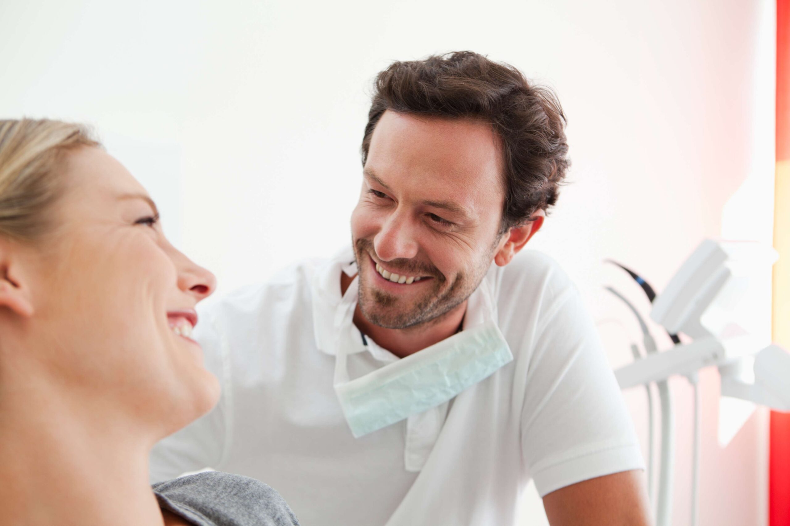 Dentist discussing dental treatment with a smiling female patient in a dental office.